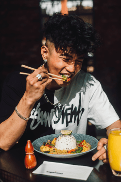 man eating curry dish with chopsticks
