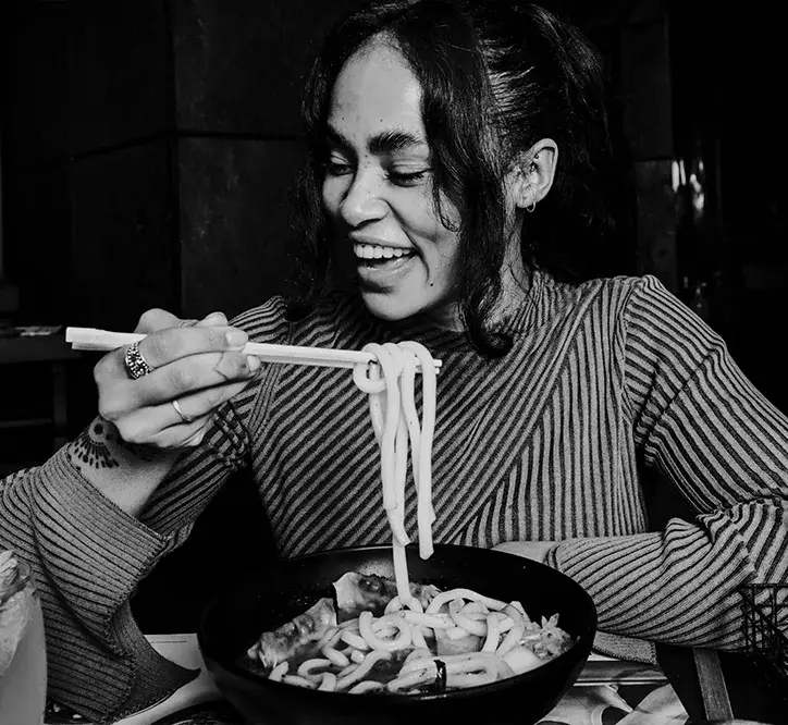 woman holding chopsticks eating noodles