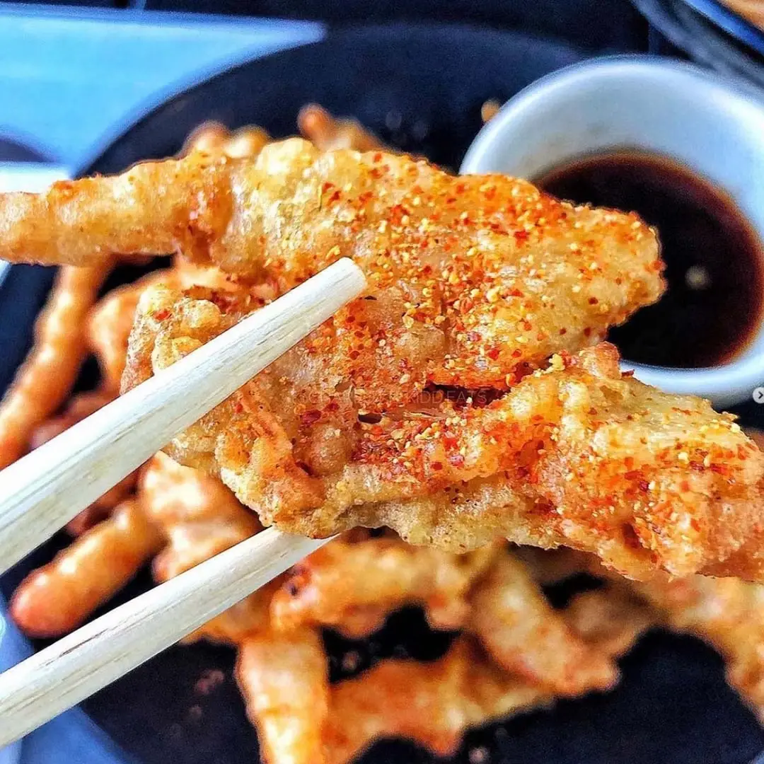 pair of chopsticks holding a piece of chilli squid