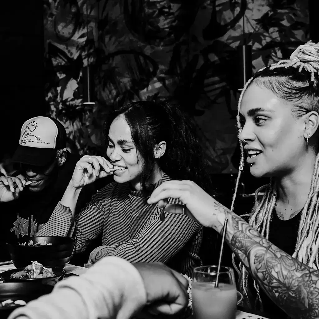 three people sat around table with food and drinks