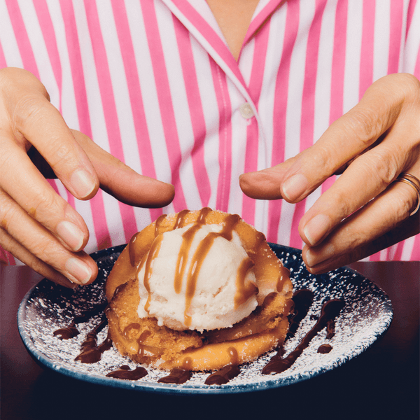 a woman in a stripy pink + white shirt enjoys the toffee apply baonut