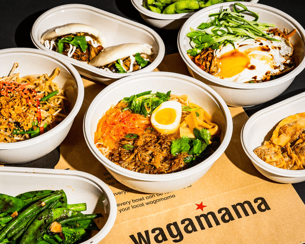 multiple wagamama takeout bowls full of food on table with takeout bag